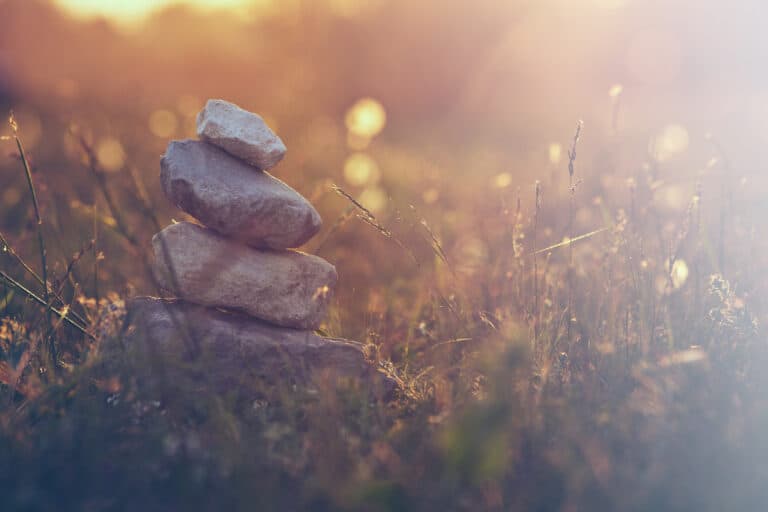 A stack of balancing stones in a sunlit meadow, symbolising calm and balance
