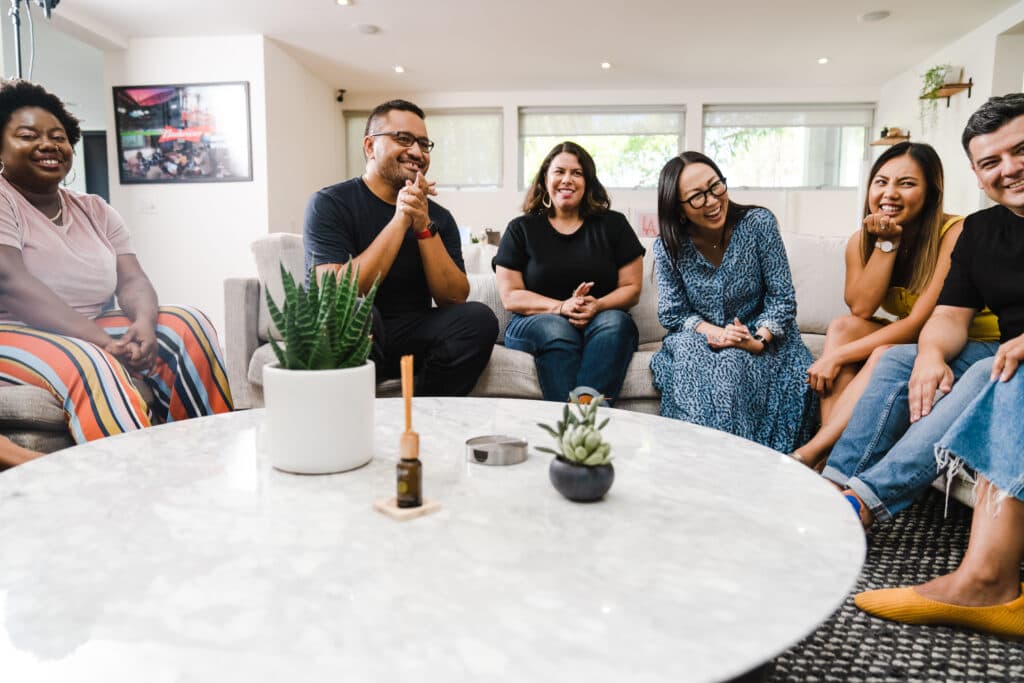 A diverse group sitting together around a couch in conversation